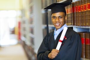 A university graduate wearing a cap and gown and holding their degree scroll.