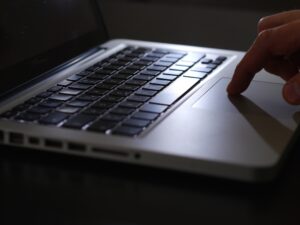 A hand using the touchpad on a silver laptop.